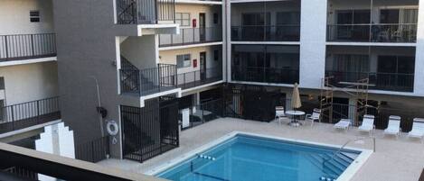 A multi-story building with a central swimming pool, balconies, and outdoor seating.