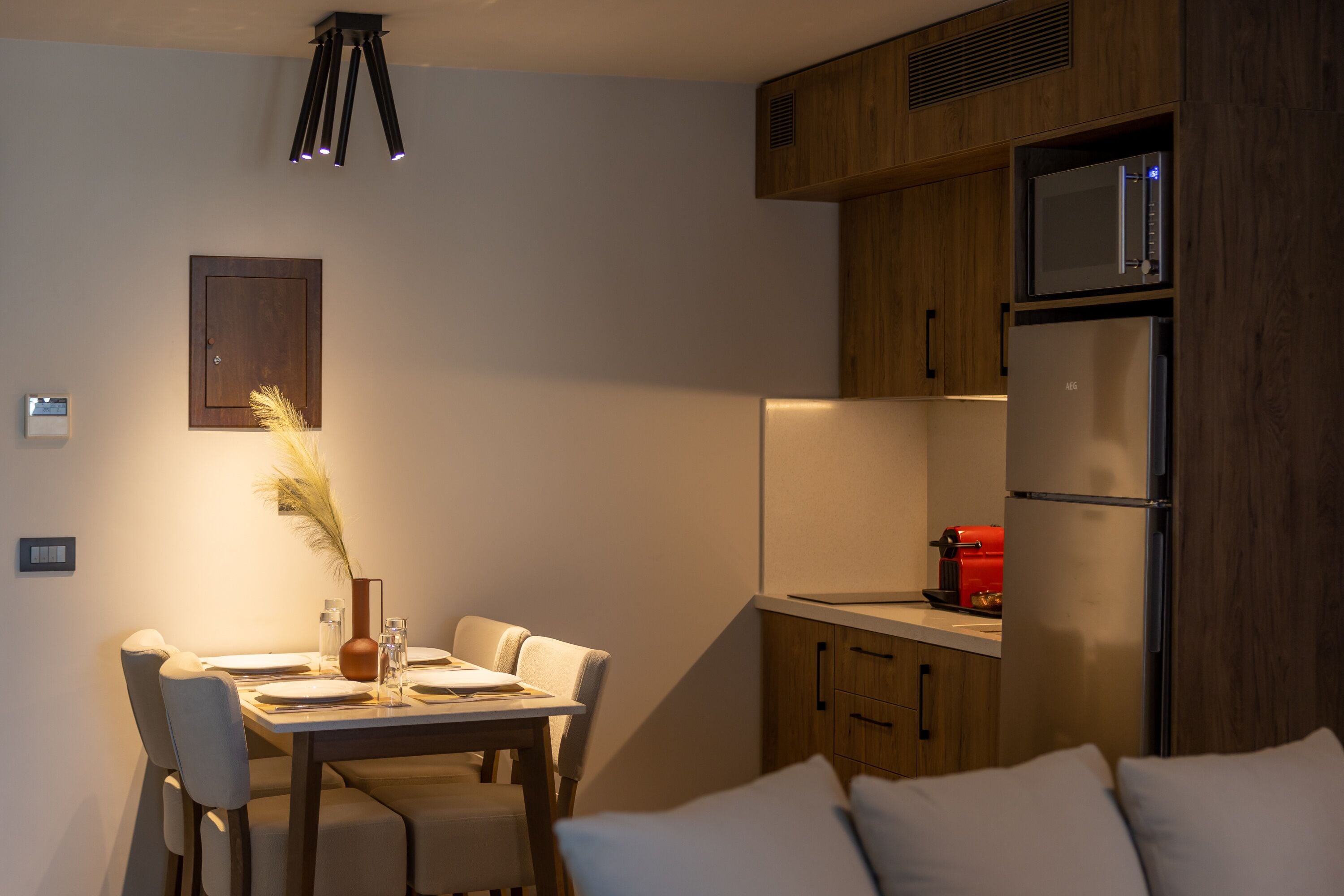 A compact kitchen with wooden cabinets, a built-in microwave, and a red coffee machine.