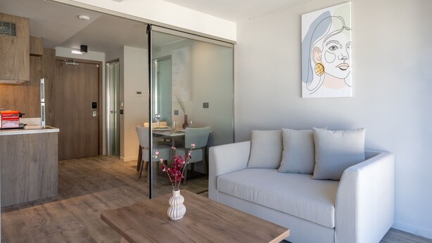 Una sala moderna con un sofá, una mesa de centro y un comedor al fondo.