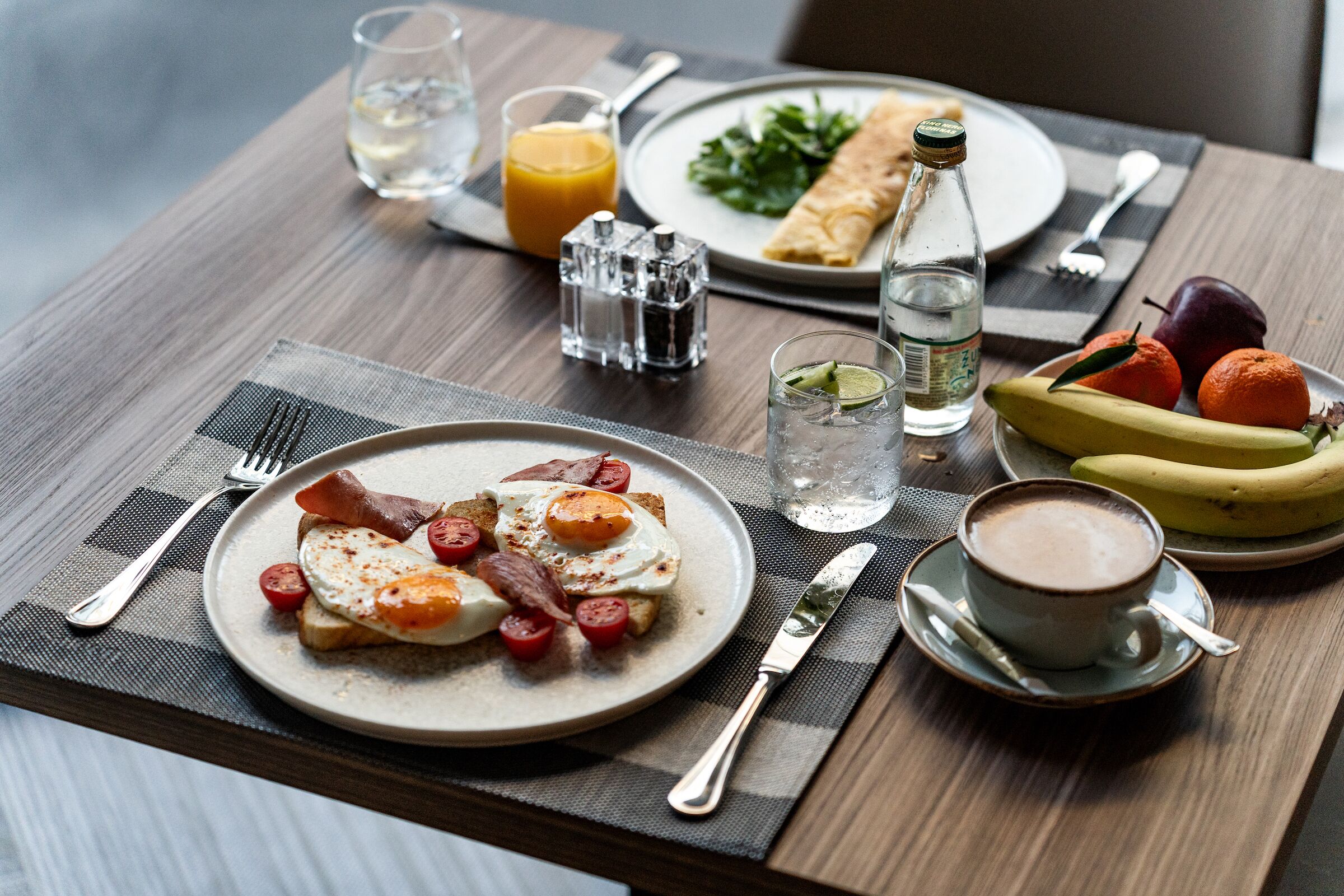Ein Frühstückstisch mit Speisen, einer Kaffeetasse und einer Wasserflasche.