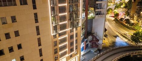 A multi-story hotel with a prominent number '507' sign, a glass facade, and a rooftop terrace.