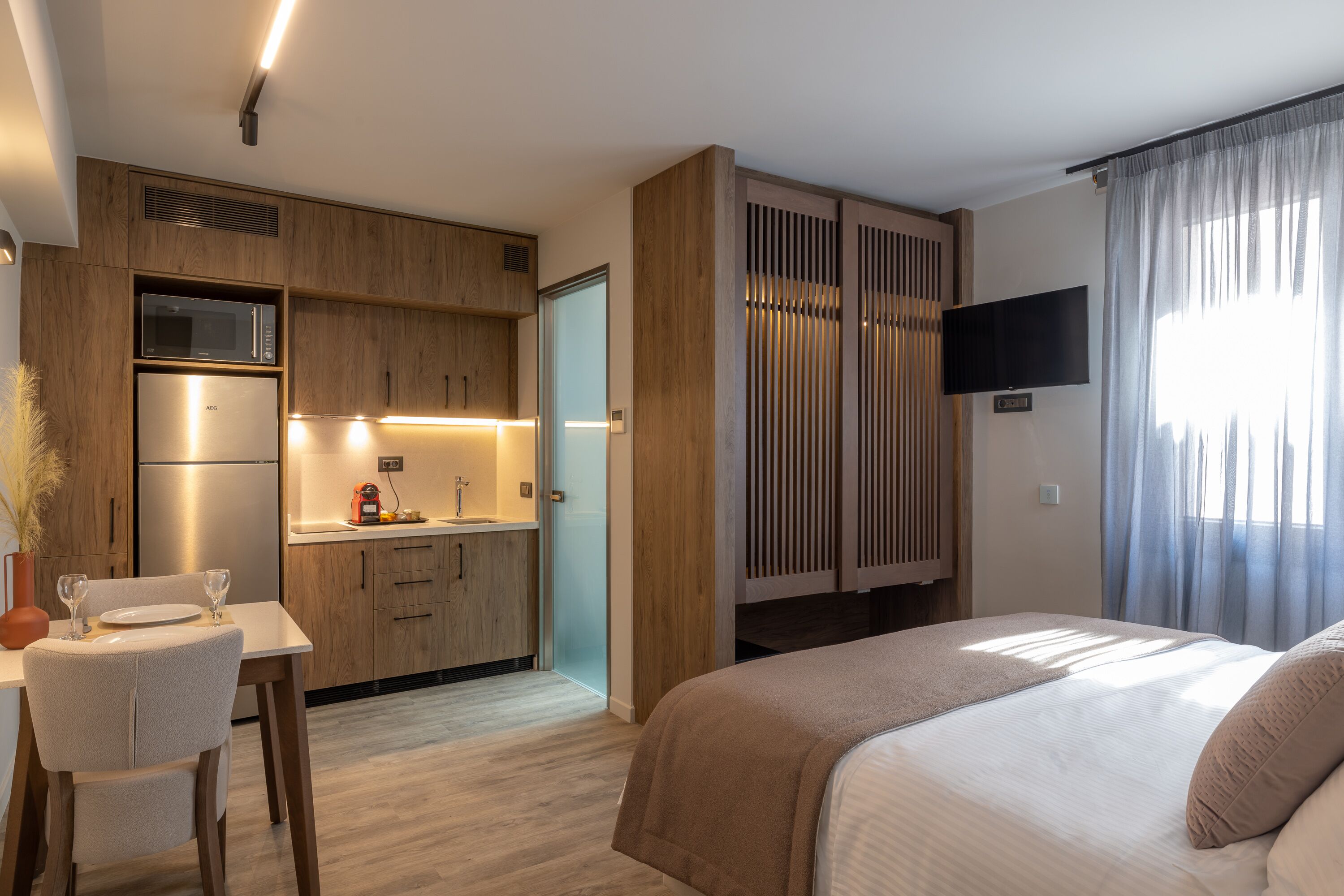 Une chambre d’hôtel moderne équipée d’une kitchenette, d’un lit et d’une télévision.