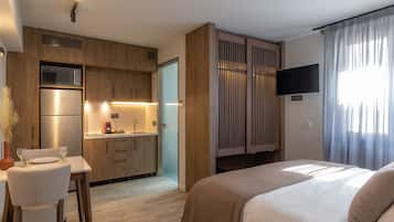 Une chambre d’hôtel moderne équipée d’une kitchenette, d’un lit et d’une télévision.