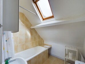 A small, modern bathroom with a skylight, a bathtub, a toilet, and a shelf with toiletries. - -HORTENSE- MAISON SABLES BLANCS Á 300M DES PLAGES (Concarneau)