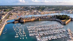 An aerial view of a harbor with numerous boats docked, a fortified structure, and a cityscape in the background. - -HORTENSE- MAISON SABLES BLANCS Á 300M DES PLAGES (Concarneau)