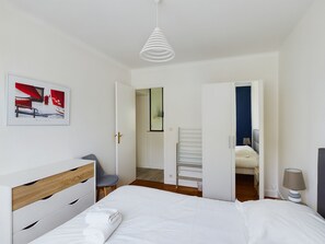 A modern hotel room with a bed, a chair, a desk, and a hanging light fixture. - -HORTENSE- MAISON SABLES BLANCS Á 300M DES PLAGES (Concarneau)