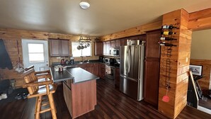 A modern kitchen with wooden cabinetry, stainless steel appliances, and a central island.