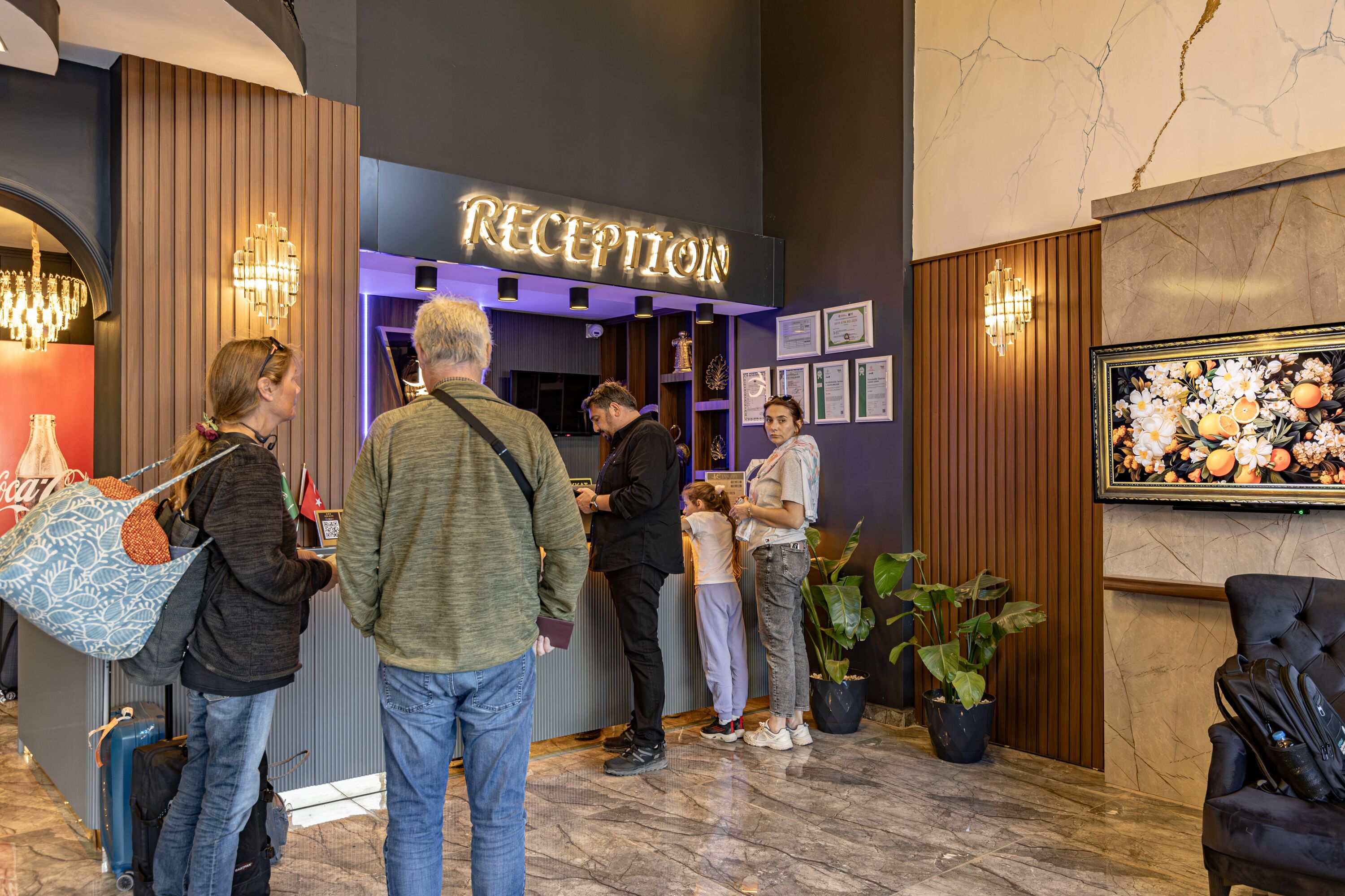 A reception area with a marble floor, a reception desk, and a framed floral artwork on the wall.