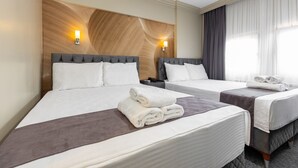 Habitación de hotel con dos camas, cada una con cabecera, mesita de noche y lámpara.
