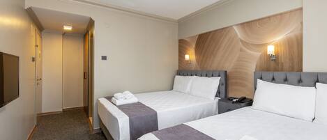 Habitación de hotel con dos camas, un escritorio y una televisión.