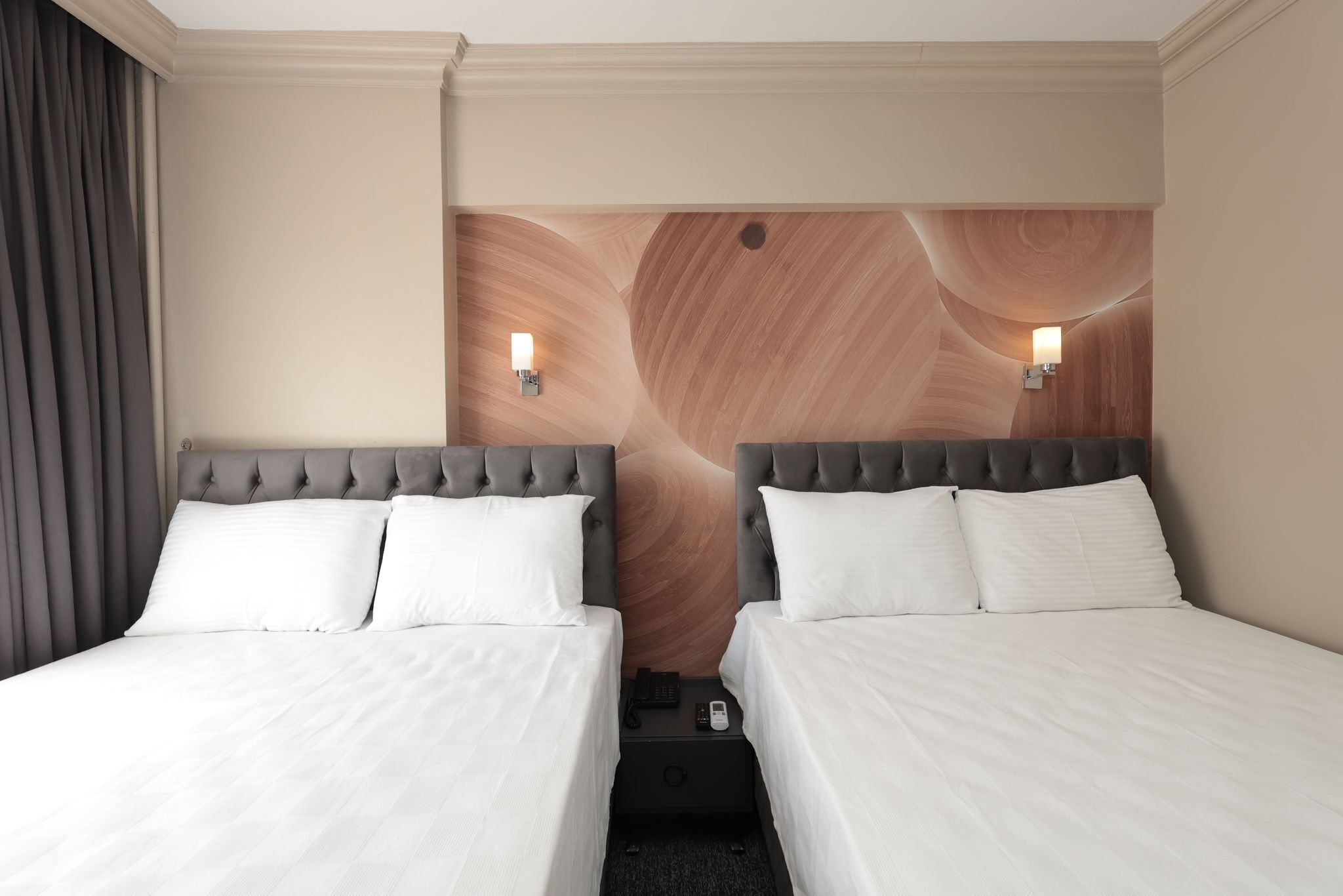 A hotel room with two beds, a wooden headboard, and bedside lamps.