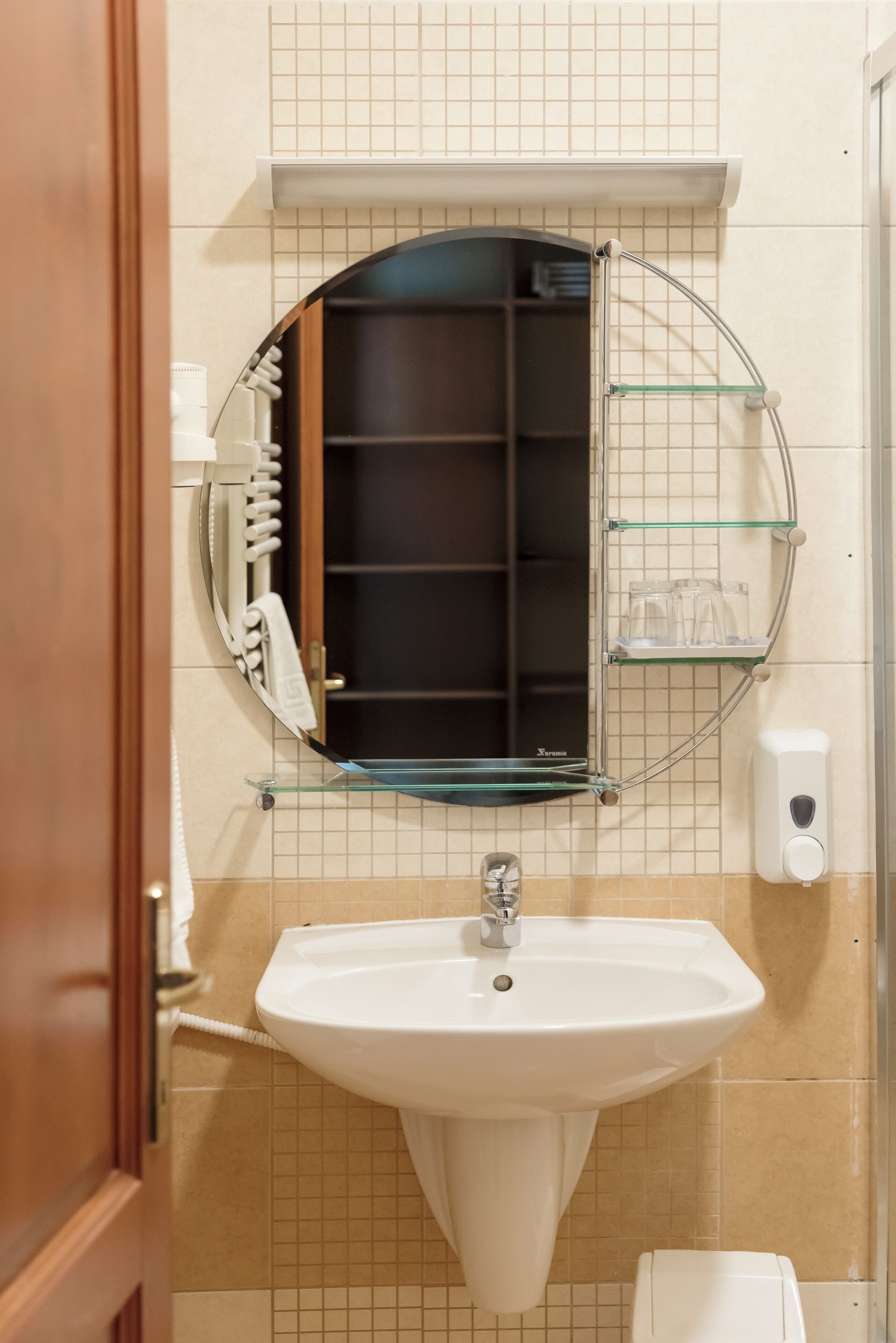 A bathroom with a white sink, a glass shelf with toiletries, and a towel rack.