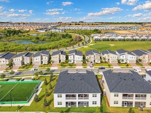 A residential area with modern houses, a green field, and a golf course in the background.
