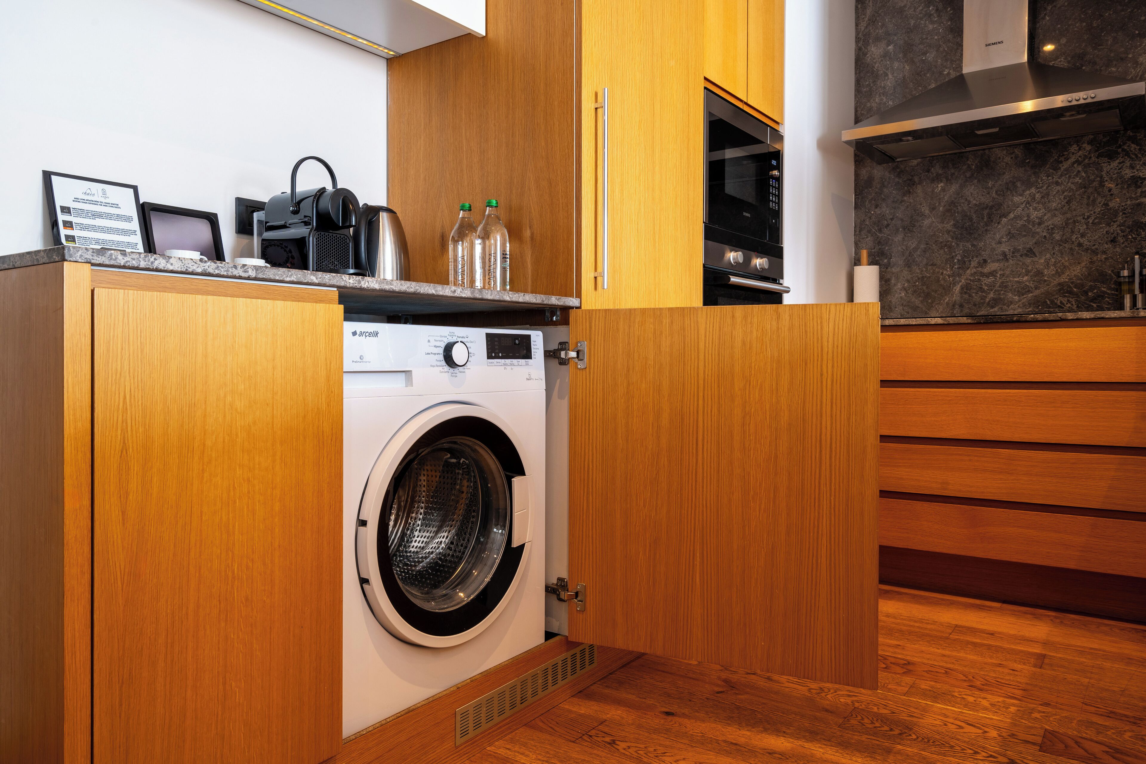 A compact kitchen with wooden cabinets, a built-in washing machine, and a stainless steel oven.