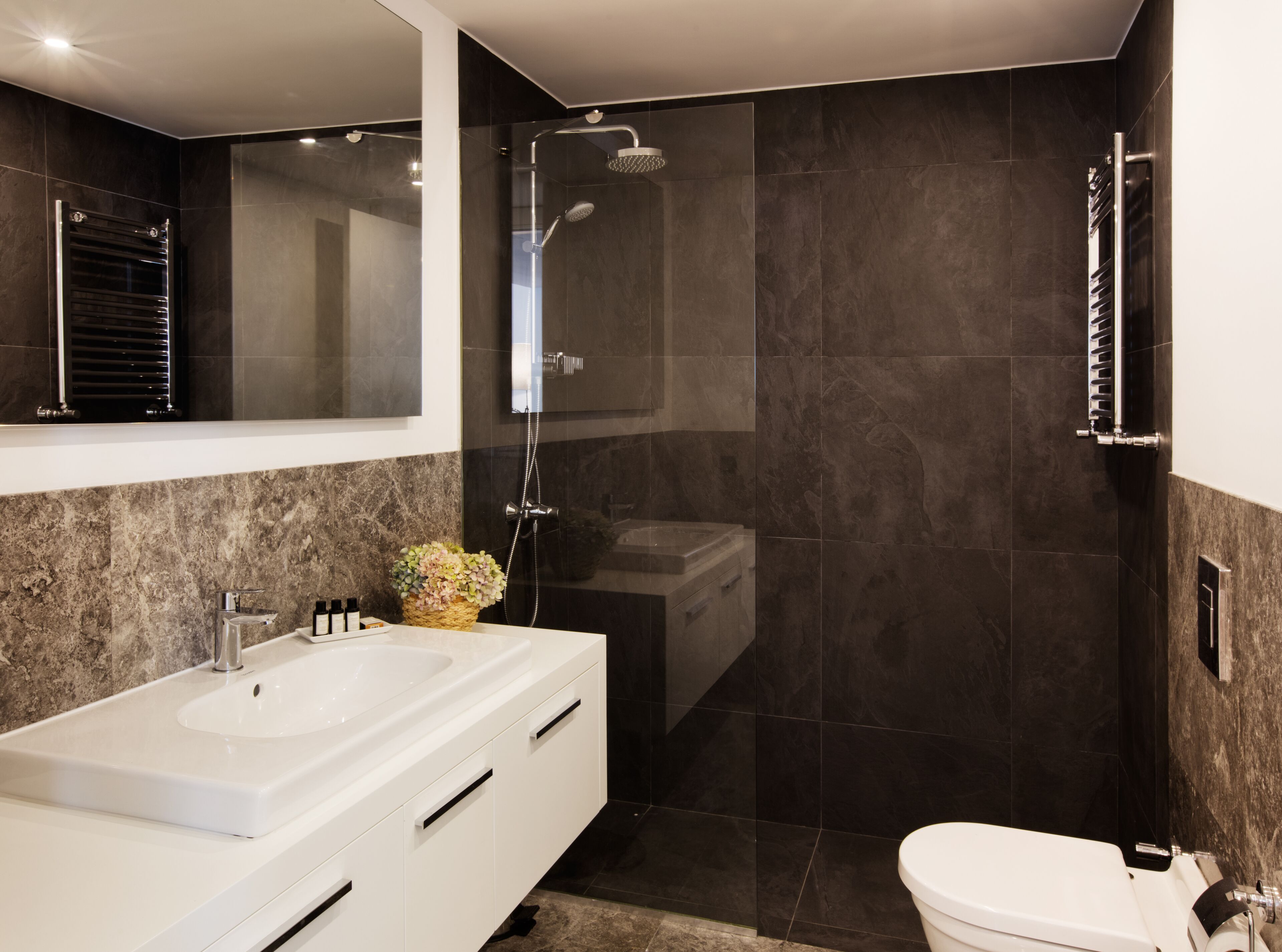 Een moderne badkamer met een groot wit wastafel, een douche met glazen wanden en een toilet.