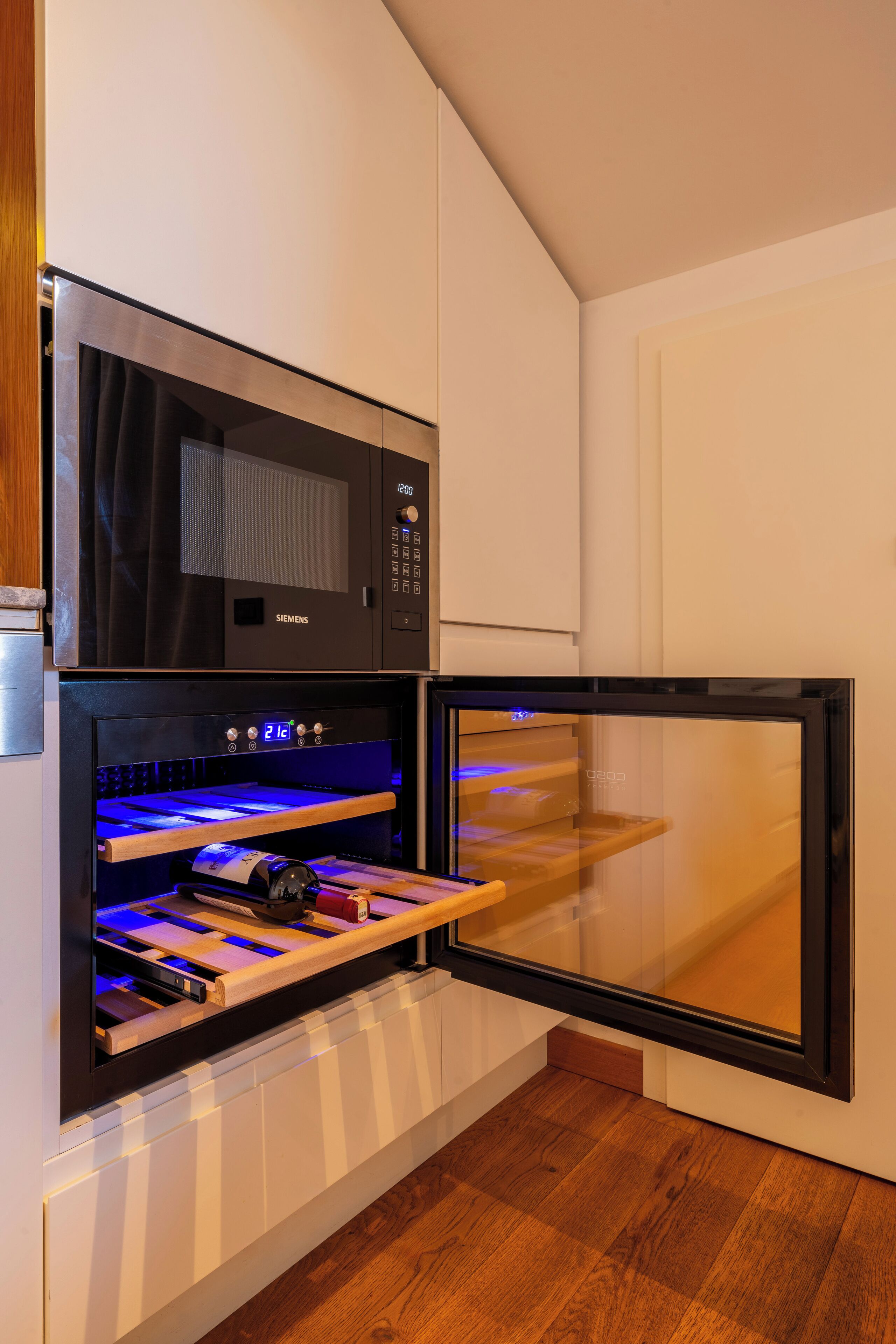 Een keuken met een magnetron, oven en een inbouw wijnkoeler.