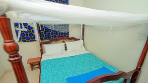 A bed with a canopy, a bedside table, and patterned wall art. - Richy Hotels and Safaris (Mbale)