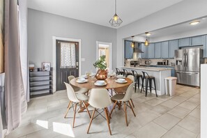 Une cuisine moderne dotée d’un îlot central, d’appareils électroménagers en acier inoxydable et d’un coin repas avec une table ronde et des chaises.