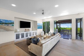 Una sala de estar moderna con sofá, televisor de pantalla plana y comedor con mobiliario exterior.