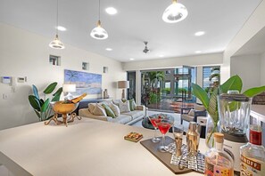 Ein modernes Wohnzimmer mit Kücheninsel, Essbereich und Blick ins Freie.