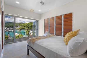 Ein Hotelzimmer mit einem großen Bett, Blick auf eine Marina und einem Balkon mit einer Glastür.