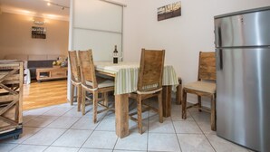 Un comedor con mesa y sillas de madera, un refrigerador y vista a una sala de estar con sofá y mesa de centro.