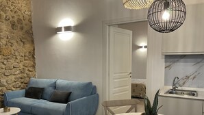 A modern living room with a blue sofa, a small round table, and a potted plant. - Rua 39 fine apartments (Syracuse)