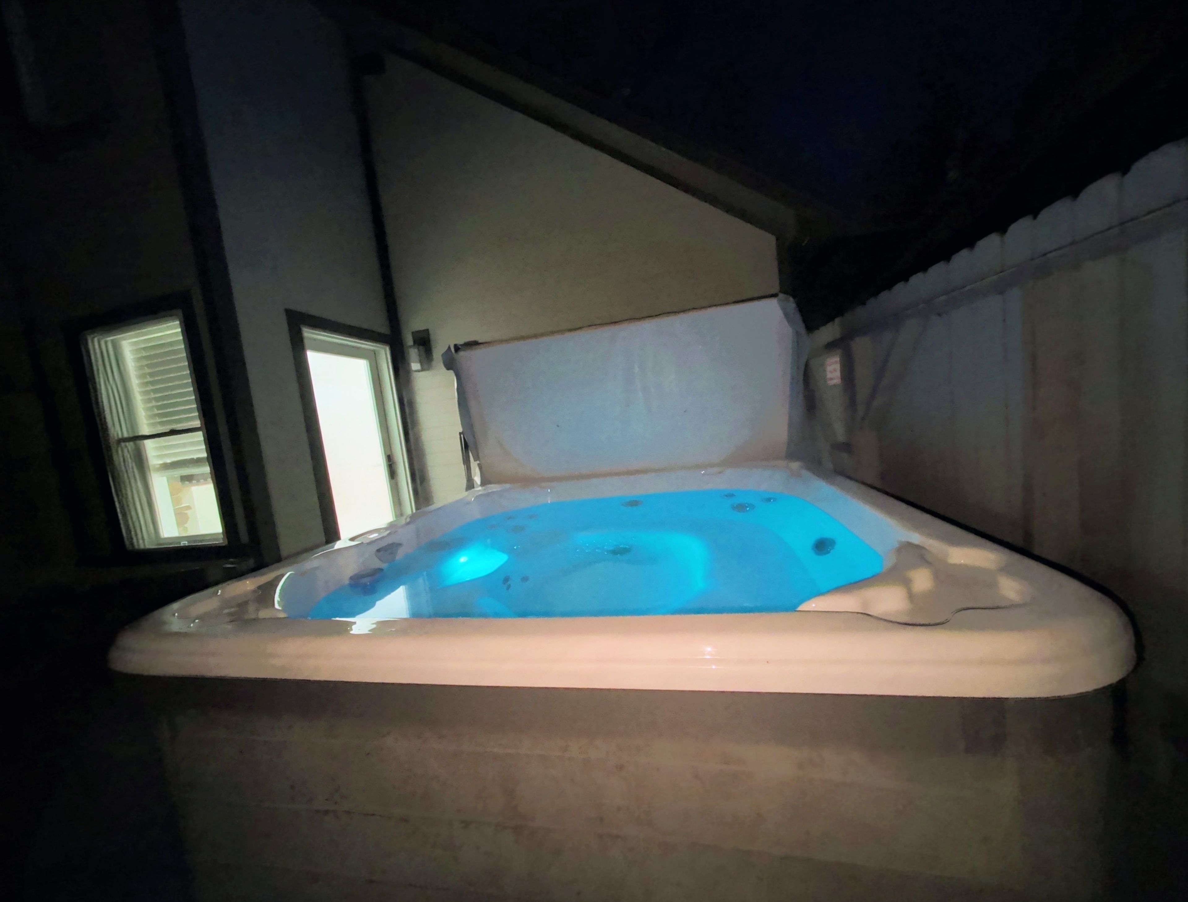 Un bain à remous avec un éclairage bleu, une fenêtre et un mur.