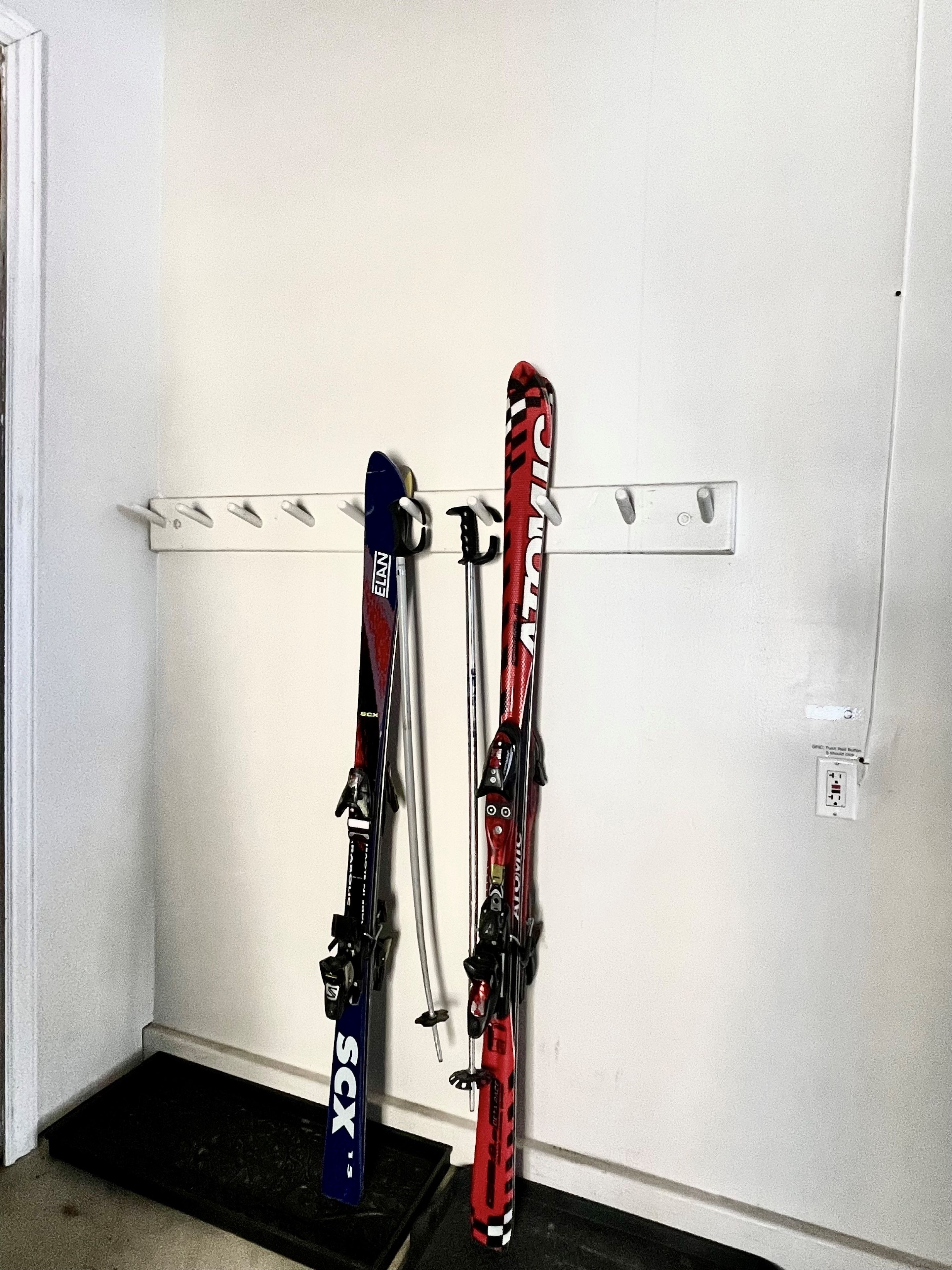 A wall-mounted ski rack with two skis.