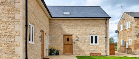 Stunning stone-clad building with a central entrance and beautifully manicured lawn.