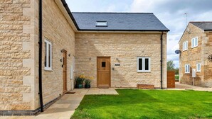 A stone building with a dark roof, a wooden door, and a small window. - The Holt (Stamford)