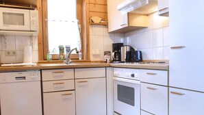Una cocina con armarios blancos, microondas integrado, cafetera y lavavajillas Siemens.