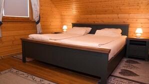 Un dormitorio con paneles de madera, una cama, mesitas de noche y una ventana con cortinas.
