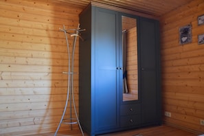A room with wooden walls and a blue wardrobe with a mirror.