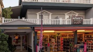 A multi-story building with a ground-level retail store named 'adam's shoes'. - Parthenon Art Executive Wing (Katerini)