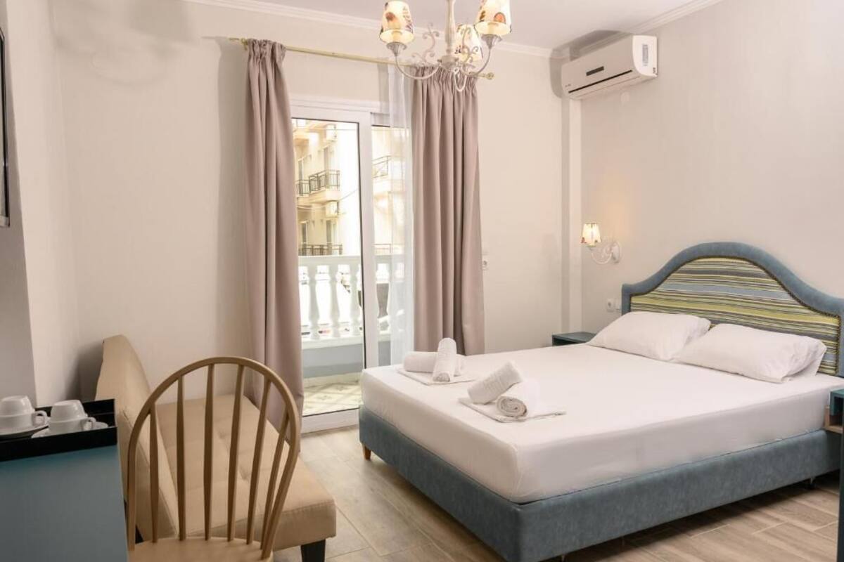 A hotel room with a bed, a chair, a desk, and a view of the outside balcony.