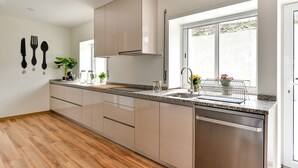 Een moderne keuken met een granieten aanrecht, roestvrijstalen apparatuur en een raam dat voor natuurlijk licht zorgt.