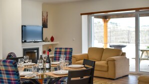 Een eetgedeelte met een tafel voor vier personen, een bank en een televisie aan de muur.