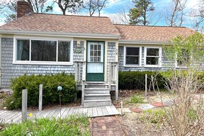Stroll up to the charming front porch, featuring a green door and white-framed windows, and enter a cozy home with a small garden area.