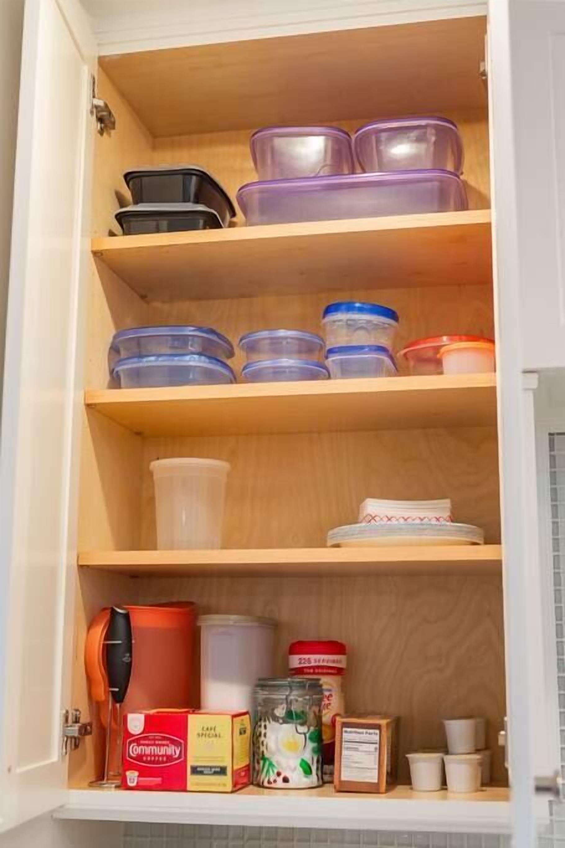 A kitchen cabinet with multiple shelves containing various containers and kitchen items.