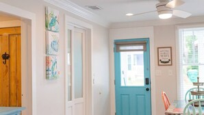 A room with a wooden door, a blue door, a dining table with chairs, and a ceiling fan.