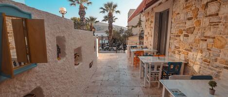 A courtyard with stone walls, outdoor seating, and palm trees.