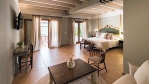 Quarto de hotel com cama, televisão, mesa de jantar e uma cadeira.