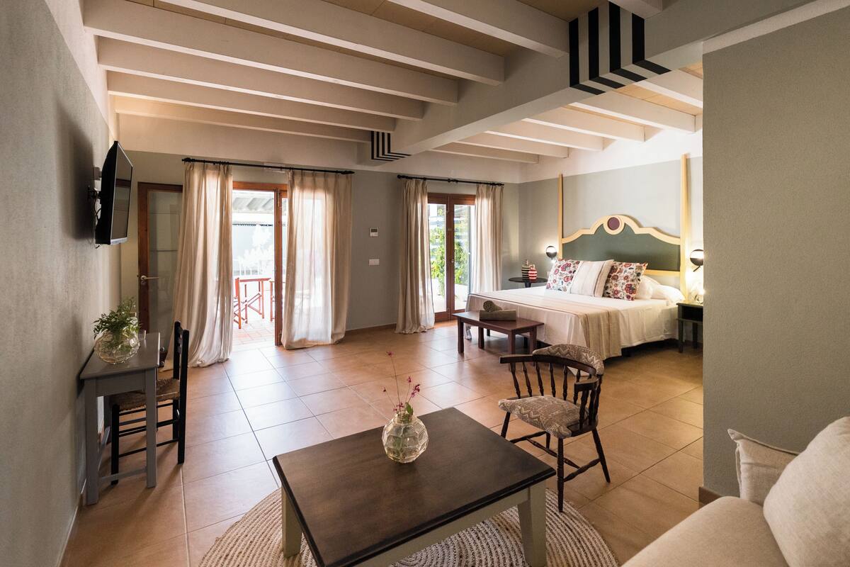 A hotel room with a bed, a TV, a dining table, and a chair.