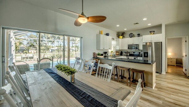 A spacious kitchen with a central island, white cabinetry, and a large window overlooking a pool. - Lazy Daze - 5 Bedroom, Sofa Bed-3.5 Bath-Private House-Heated Pool-Waterfront (Cape Coral)
