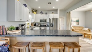 A modern kitchen with white cabinets, a marble countertop, and a central island with stools. - Lazy Daze - 5 Bedroom, Sofa Bed-3.5 Bath-Private House-Heated Pool-Waterfront (Cape Coral)