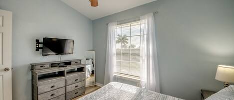 A bedroom with a bed, a dresser, a TV, and a ceiling fan.