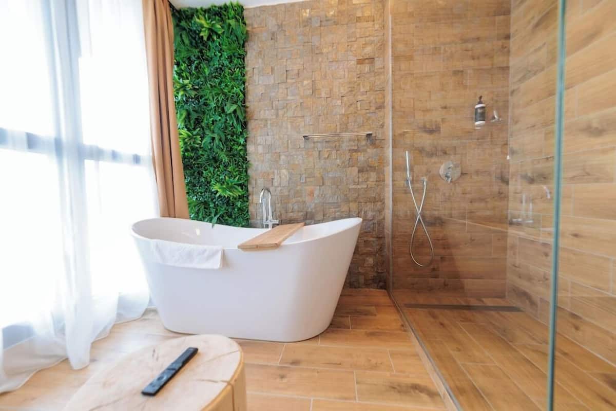 Une salle de bain moderne avec une baignoire sur pieds, une douche à parois de verre et un mur d’accent vert.