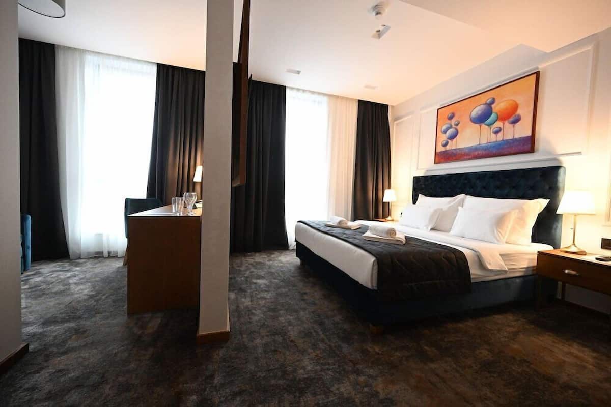 Une chambre d’hôtel avec un grand lit, un bureau, une chaise et un tableau au mur.
