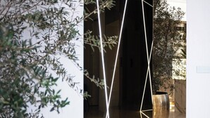 A modern interior with geometric light installations, a large metallic planter, and a doorway leading to another space. - Luxury Penthouse In Downtown (Budapest)